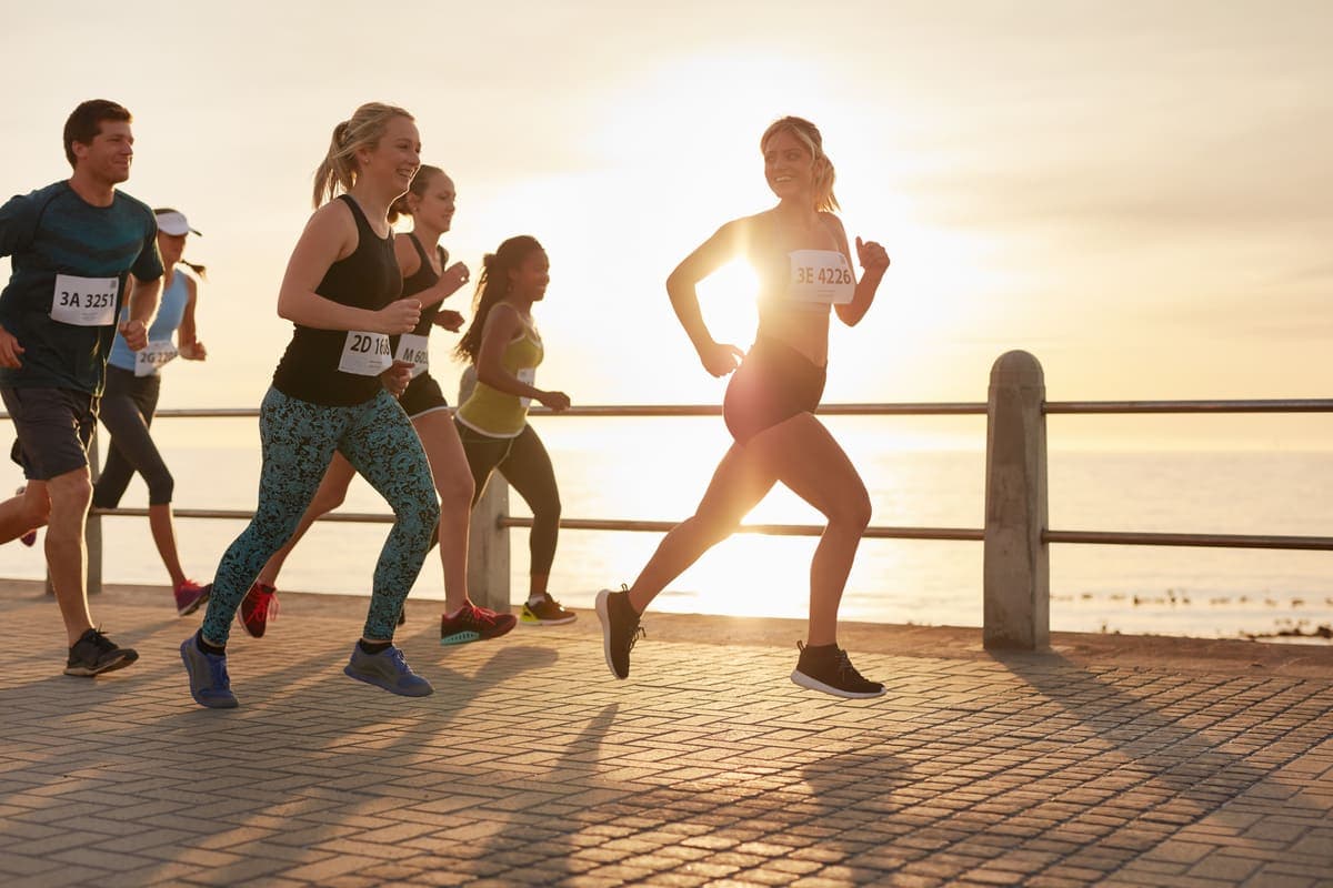 Coureurs souriants avec leurs dossards en bord de mer au coucher du soleil